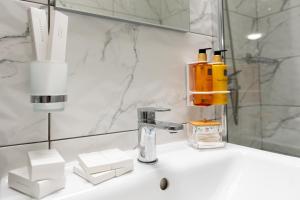 a bathroom with a sink with a soap dispenser at Soni Exclusive Apartments 1218 Plaza with Private Parking & Self Check-in in Bucharest +25 photos