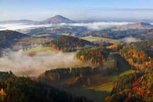 ein nebliges Tal im Herbst mit Bäumen und Bergen in der Unterkunft Apartmán - Dům Českého Švýcarska in Krásná Lípa