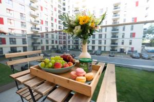 a table with a bowl of fruit and a vase of flowers at Soni Exclusive Apartments 1218 Plaza with Private Parking & Self Check-in in Bucharest