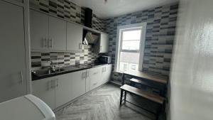 a kitchen with white cabinets and a sink and a window at stay inn - shared flat in Portadown in Portadown