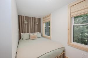 a small bedroom with a bed and a window at BrookHaus - Modern Cabin Stay at Harvard Brook in Lincoln
