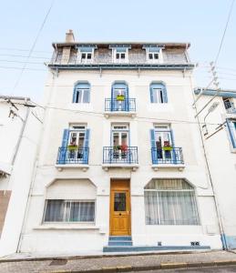un edificio blanco con ventanas azules y una puerta en Côté Cour - Lourdes, en Lourdes