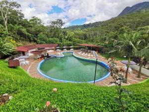 a swimming pool in a resort with mountains in the background at Hotel y termales Las Heliconias in Zetaquira