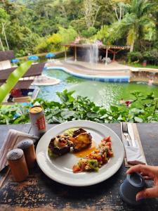 a plate of food on a table in front of a pool at Hotel y termales Las Heliconias in Zetaquira