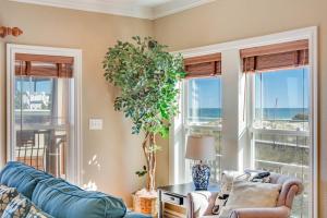 sala de estar con sofá azul y ventanas en Happy Days Formerly Cowabungalow, en Kill Devil Hills