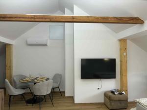 a dining room with a table and a tv on a wall at Apartma Lavanda in Zavrč