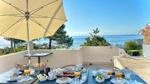 a table with food and an umbrella and the ocean at Residence Canella in Sari Solenzara