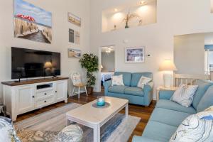 a living room with blue furniture and a flat screen tv at Harrells Retreat in Nags Head