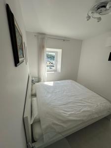 a white bedroom with a bed and a window at Villa Nada in Banići