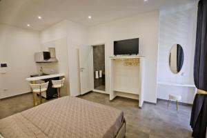 a bedroom with a bed and a television and a kitchen at Dante Luxury Rooms in Naples