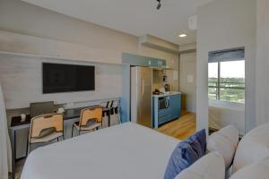 a bedroom with a bed and a kitchen with a table at Roomo Transamerica SP Brooklin Santo Amaro in Sao Paulo