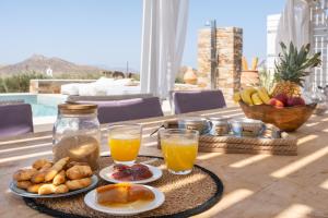 a table topped with plates of food and orange juice at Revery Villa in Ios Chora