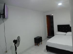 ein weißes Schlafzimmer mit Bett und Ventilator in der Unterkunft Hotel Kenisoni in Ibagué