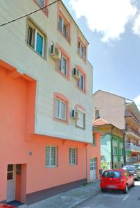 a red car parked in front of a building at City Center Sweet Apartment in Niš