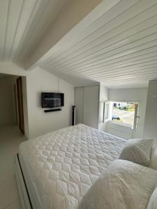 a white bedroom with a large bed and a television at La Villa Delphine in Vaux-sur-Mer