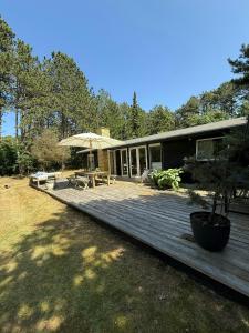 una casa con terrazza in legno e ombrellone di Wooden Cottage Near The Beach In Odsherred ad Asnæs