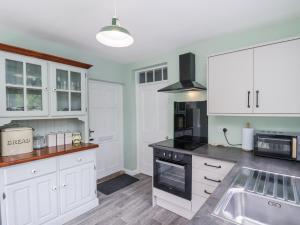 una cucina con mobili bianchi e un forno a piano cottura di 2 Whinstone Cottage a Whitby Altre 38 foto