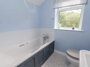 bagno con vasca, servizi igienici e finestra di 2 Whinstone Cottage a Whitby