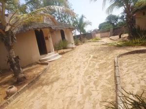 a dirt road next to a house with a palm tree at Auberge chambres d'hôtes mamadou in Fatick