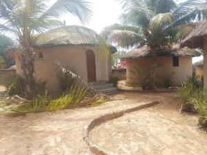 a small house with two palm trees in front of it at Auberge chambres d'hôtes mamadou in Fatick