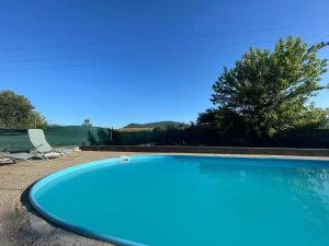 a blue swimming pool with a chair and a tree at Autocamp Free Star - Chatky a Bungalovy in Strachotín