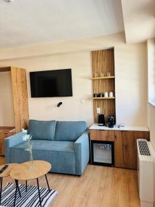 Una sala de estar con un sofá azul y un televisor. en TASY Guest House, en Bitola