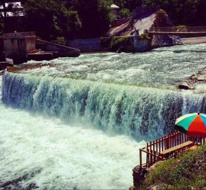 a waterfall with an umbrella in front of a river at Hotel popeyes and restaurant in Chitra