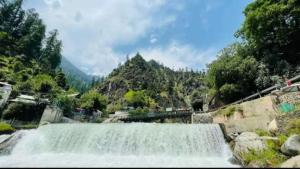 a waterfall in front of a mountain with trees at Hotel popeyes and restaurant in Chitra