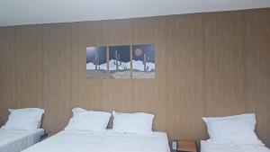 two beds in a room with two paintings on the wall at Nobre Flats 201 in Petrolina