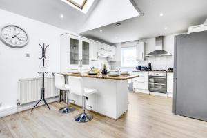 a kitchen with a counter and a clock on the wall at Wimbledon 3Bath Sleeps7 AELTC in London