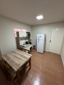a small kitchen with a table and a refrigerator at Container 260 in Cambará