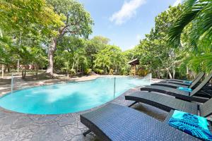 a large swimming pool with chairs and trees at Island Gardens Family Escape, Pool & Car included in Nassau