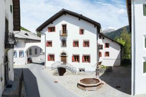 una casa bianca con finestre rosse e un cortile di Chesa Michel a Bever