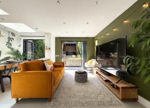 a living room with a couch and a tv at London Queen's Park with cinema & gaming room in London