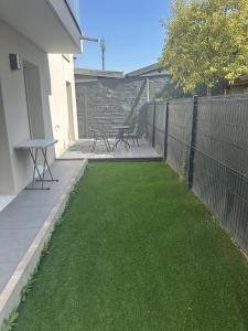 eine Terrasse mit zwei Picknicktischen und grünem Gras in der Unterkunft Cozy apartment with garden, massage in Romainville