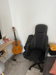 ein schwarzer Stuhl neben einer Gitarre in einem Raum in der Unterkunft Cozy apartment with garden, massage in Romainville + 8 Fotos