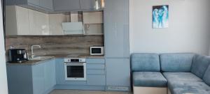 a kitchen with blue cabinets and a couch in a room at Ela, Kedar 5 in Sveti Vlas