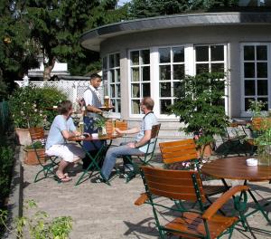 een groep mensen die aan tafel zitten in een tuin bij Hotel Exquisit in Minden
