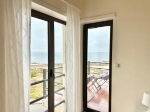 a door leading to a balcony with a view of the ocean at Deluxe Oceanfront - Vue Sur la Mer in Peniche