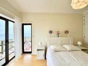 a bedroom with a white bed and a large window at Deluxe Oceanfront - Vue Sur la Mer in Peniche
