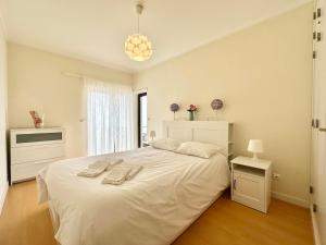 a bedroom with a white bed with two towels on it at Deluxe Oceanfront - Vue Sur la Mer in Peniche
