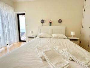 a white bedroom with a large white bed with two windows at Deluxe Oceanfront - Vue Sur la Mer in Peniche