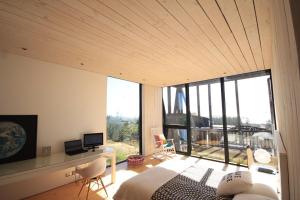 a bedroom with a bed and a desk and a large window at Punta de Lobos Black House in Pichilemu