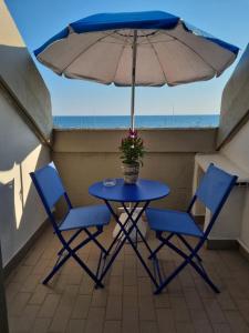 - une table avec deux chaises et un parasol sur le balcon dans l'établissement A un passo dal mare - Vista mare, à Marina di Massa