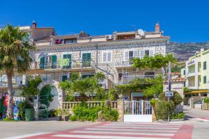 a large white building with balconies on a street at Apartments Amfora 2 in Podgora