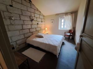 a bedroom with a bed and a brick wall at La Maison Des Bouissonne in Maillane