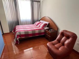 ein Schlafzimmer mit einem Bett und einem Ledersessel in der Unterkunft Departamento entero dos habitaciones completamente amoblado in Arequipa