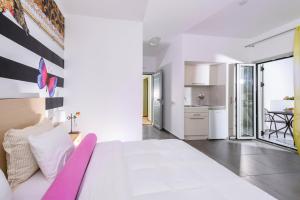 a white bedroom with a large bed and a kitchen at Angela Studios Apartments in Sissi