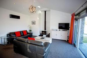 a living room with a couch and a tv at Luxury on Rutherford in Hanmer Springs