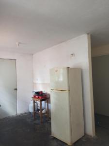 a white refrigerator in a room with a table at Casita a 10 min del aeropuerto Internacional de Monterrey in Pesquería